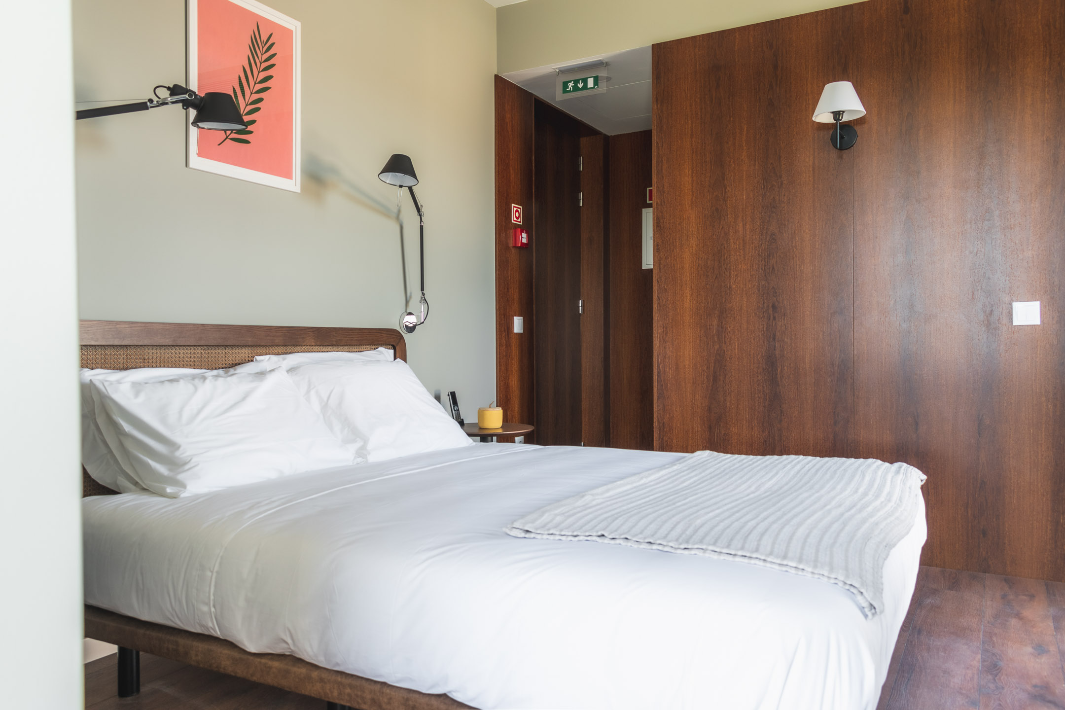 A bedroom with a large bed, tv, table and windows.